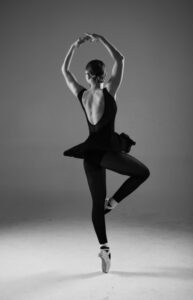 a young female ballet student in classic black ballet dance leotard is pirouetting