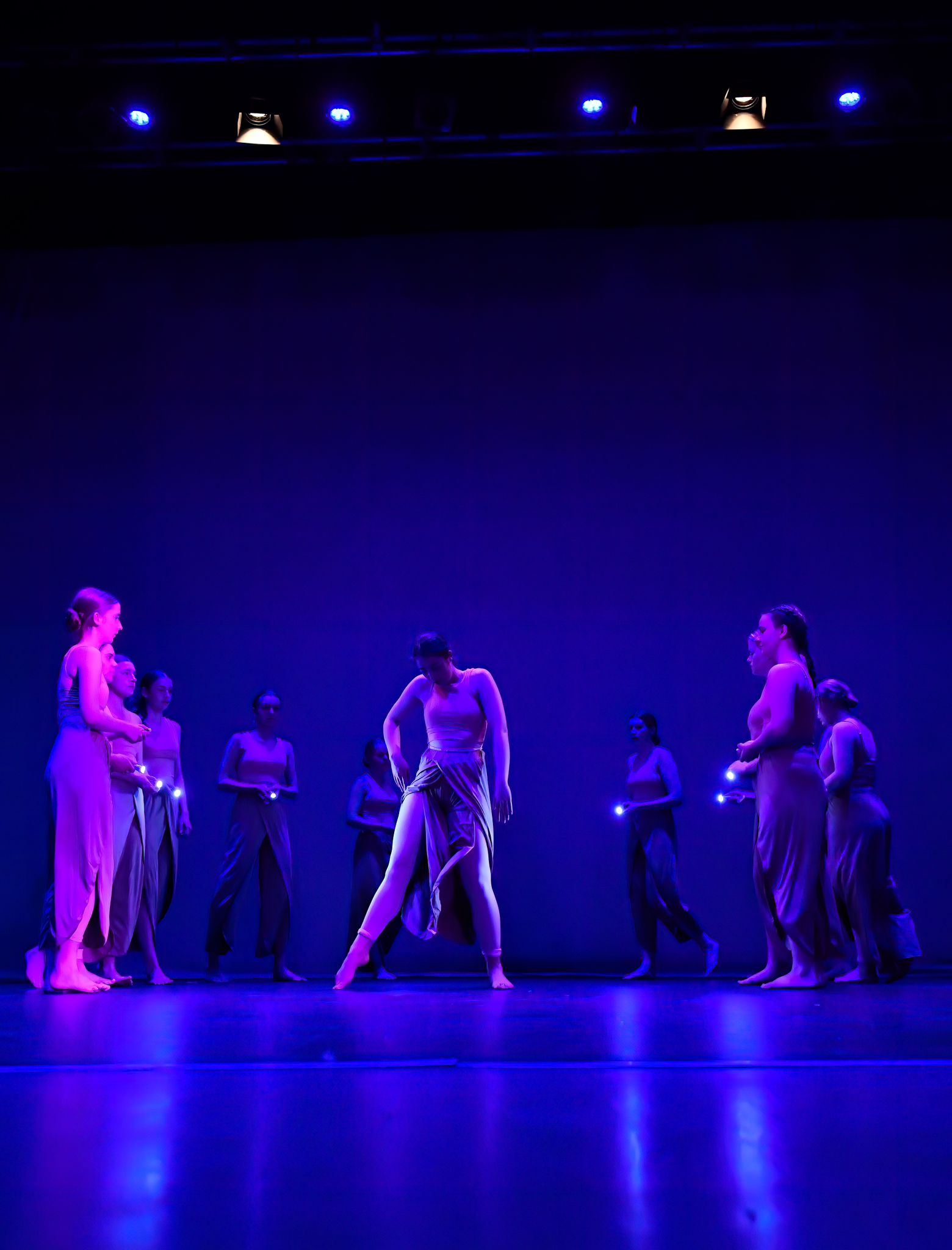 a group of teenage contemporary dance students are on stage under dramatic blue lighting, they are performing their dance routine for parents as part of a performance night for Ruth Shine School of Dance in Dublin, Ireland