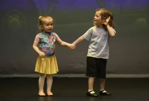 photo of pre-school age boy and girl on stage performing for parents at a ballet school